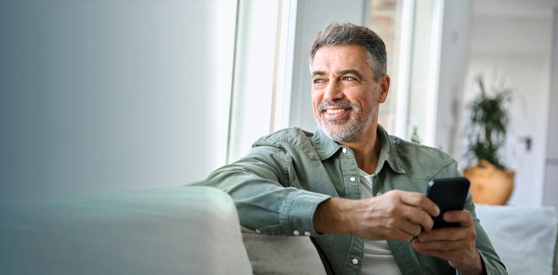 A smiling patient at home, holding a phone